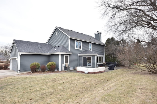 rear view of property with a garage, a patio area, and a lawn