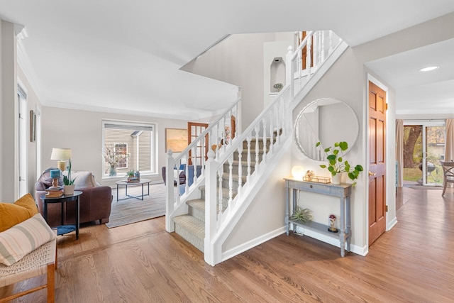 stairs featuring hardwood / wood-style floors and ornamental molding