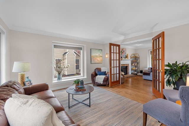 living room featuring ornamental molding, light hardwood / wood-style flooring, a fireplace, and french doors