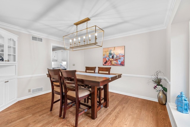 dining room with crown molding and light hardwood / wood-style flooring