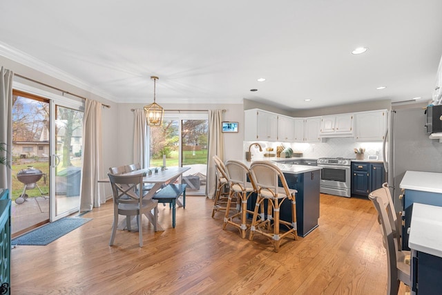 kitchen featuring stainless steel gas stove, a kitchen breakfast bar, a center island, white cabinets, and decorative light fixtures