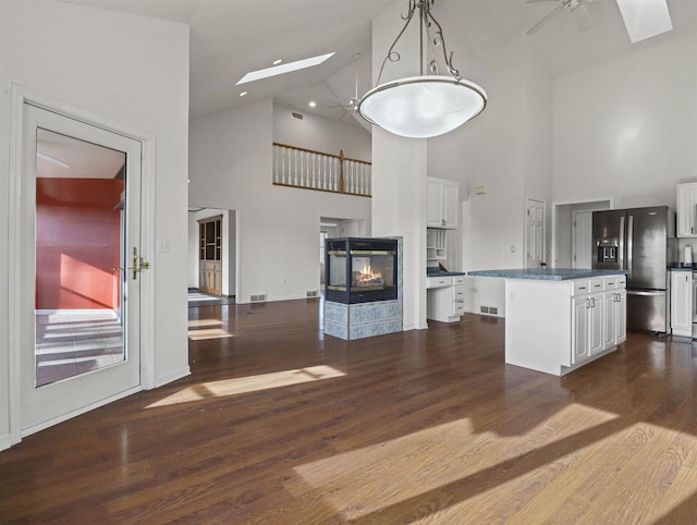 kitchen featuring white cabinetry, a skylight, a center island, and stainless steel fridge with ice dispenser