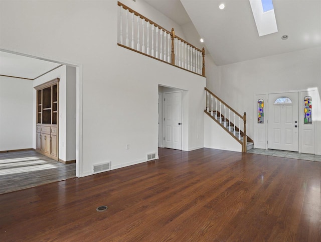 foyer entrance with a skylight, high vaulted ceiling, and dark hardwood / wood-style floors