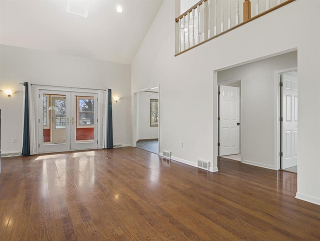 unfurnished living room featuring french doors, a towering ceiling, and dark hardwood / wood-style floors