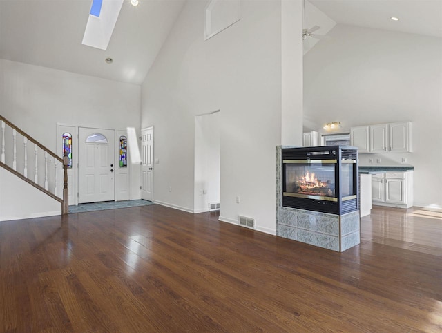 unfurnished living room with dark wood-type flooring, high vaulted ceiling, ceiling fan, and a multi sided fireplace