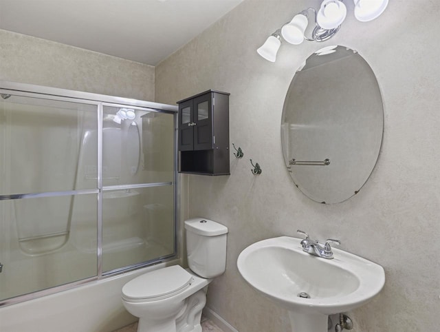 full bathroom featuring bath / shower combo with glass door, toilet, and sink