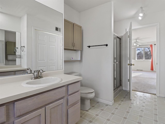 bathroom with a shower with door, vanity, ceiling fan, and toilet