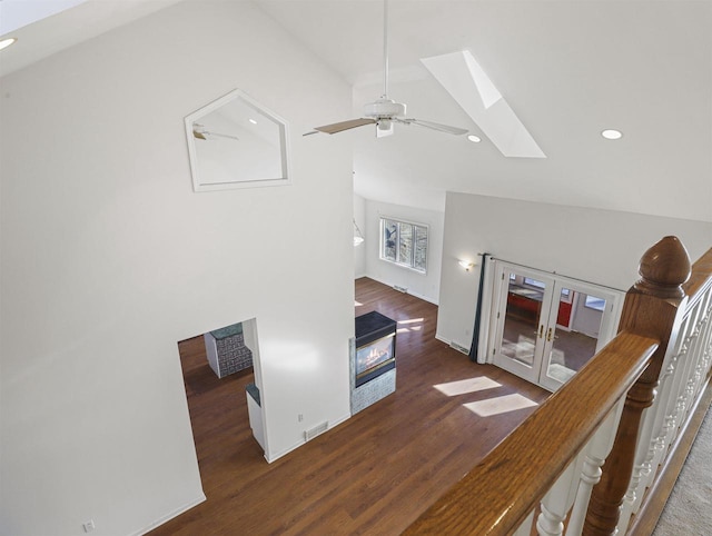 living room with dark wood-type flooring, a skylight, high vaulted ceiling, and ceiling fan