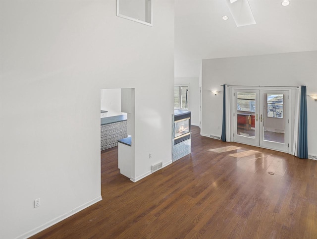 unfurnished living room with french doors, dark hardwood / wood-style floors, and a high ceiling