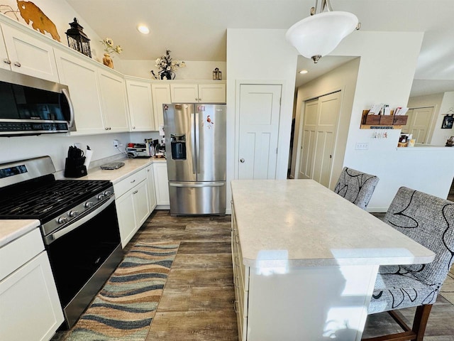 kitchen featuring appliances with stainless steel finishes, white cabinetry, hanging light fixtures, a center island, and dark hardwood / wood-style flooring