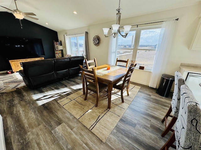 dining space with dark wood-type flooring, ceiling fan with notable chandelier, and vaulted ceiling