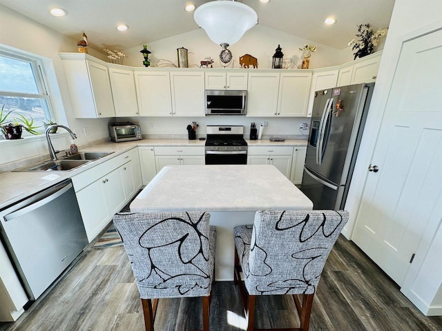 kitchen with stainless steel appliances, a kitchen island, sink, and white cabinets