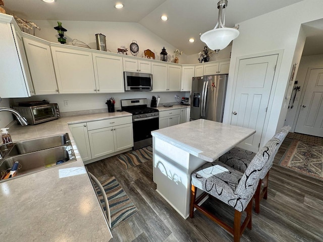 kitchen featuring sink, white cabinetry, vaulted ceiling, appliances with stainless steel finishes, and pendant lighting