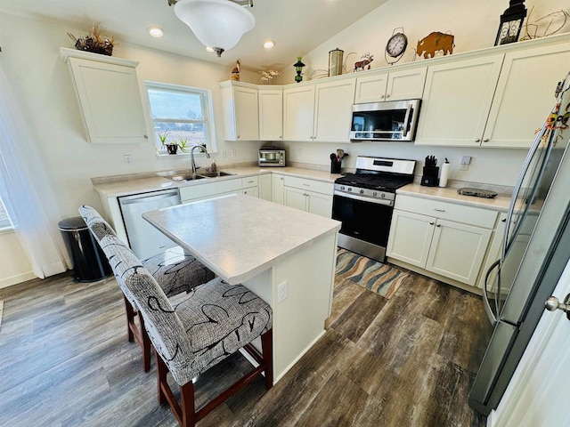 kitchen featuring sink, dark wood-type flooring, appliances with stainless steel finishes, white cabinetry, and vaulted ceiling