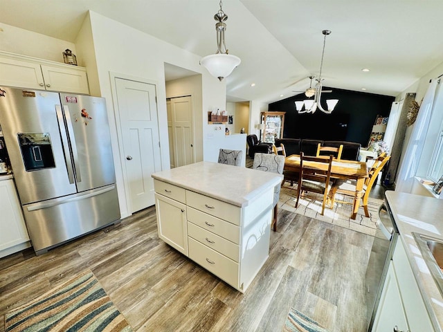 kitchen featuring hanging light fixtures, vaulted ceiling, stainless steel fridge, and light hardwood / wood-style floors