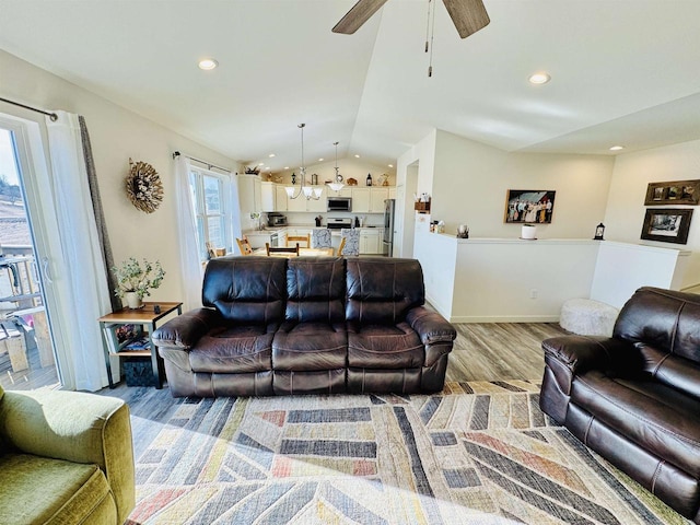 living room featuring vaulted ceiling, ceiling fan, and light wood-type flooring