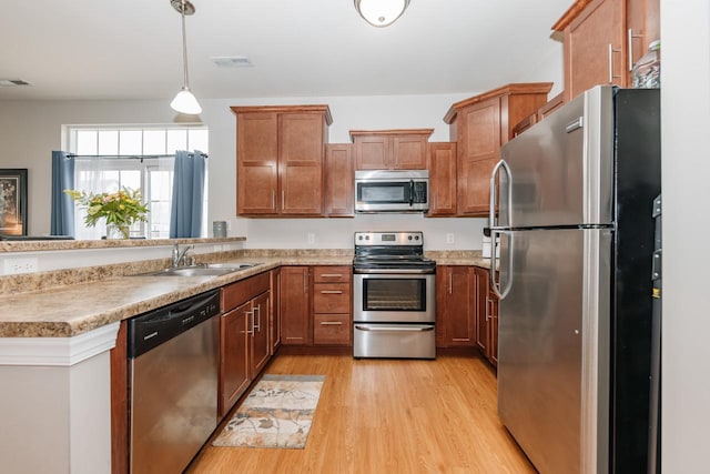 kitchen featuring pendant lighting, sink, light wood-type flooring, and appliances with stainless steel finishes