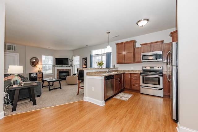 kitchen with decorative light fixtures, a wealth of natural light, stainless steel appliances, and kitchen peninsula