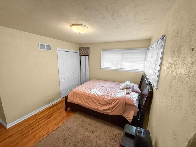 bedroom with hardwood / wood-style floors, a closet, and a textured ceiling