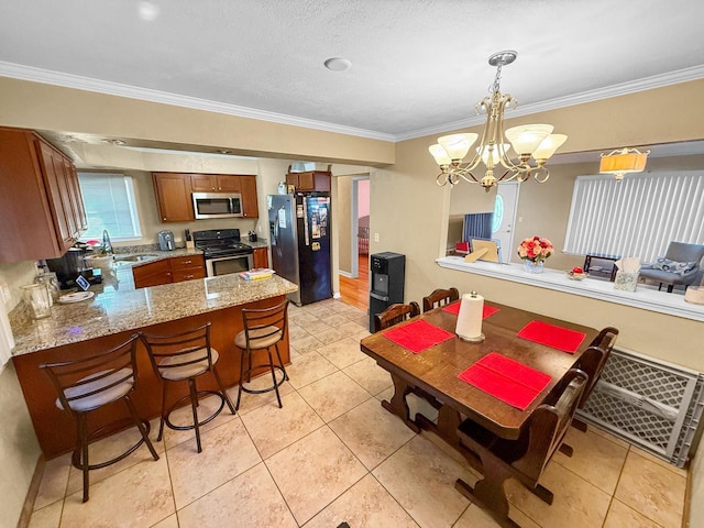 kitchen featuring pendant lighting, light stone counters, kitchen peninsula, stainless steel appliances, and crown molding