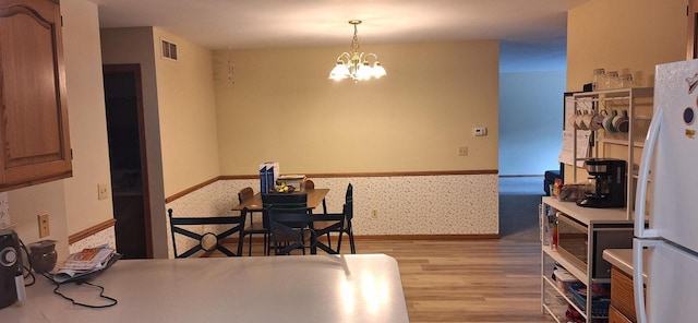 dining space with a chandelier and light hardwood / wood-style floors