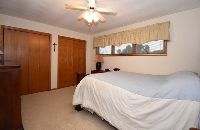 bedroom with light carpet, two closets, and ceiling fan