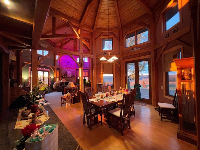 dining room with lofted ceiling with beams, wood finished floors, wood ceiling, a healthy amount of sunlight, and french doors