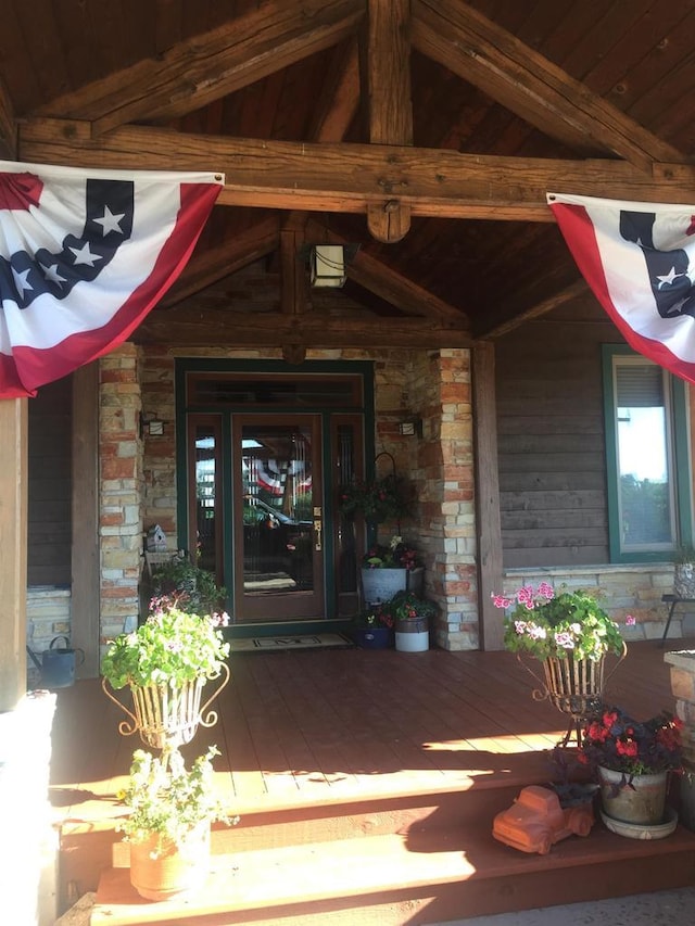 entrance to property with a porch and stone siding