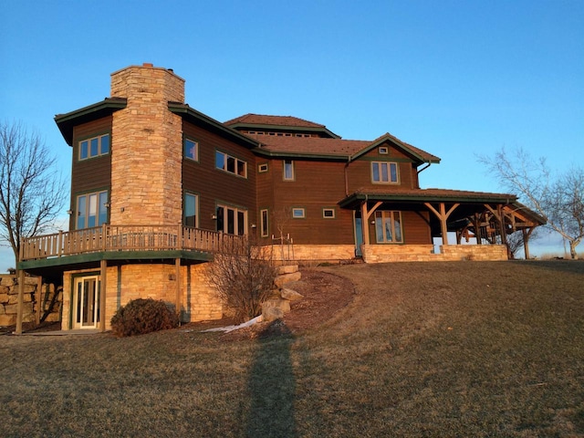 rear view of house featuring a yard, a chimney, and a wooden deck