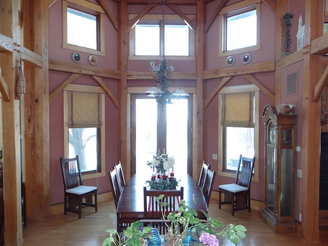 dining room with visible vents, a towering ceiling, an inviting chandelier, french doors, and light wood-style floors