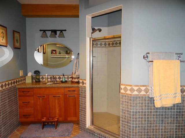 bathroom with a stall shower, a wainscoted wall, tile walls, and tile patterned floors