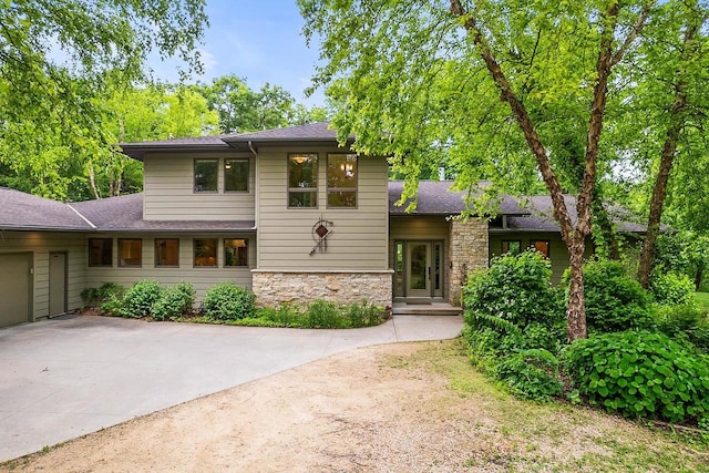 E4725 Riverside Dr, Spring Green, WI 53588 - split level home with stone siding, roof with shingles, an attached garage, and concrete driveway