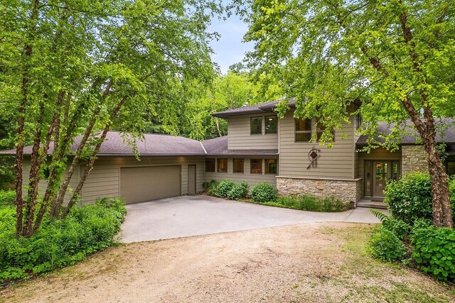E4725 Riverside Dr, Spring Green, WI 53588 - view of front facade featuring concrete driveway, an attached garage, stone siding, and a shingled roof