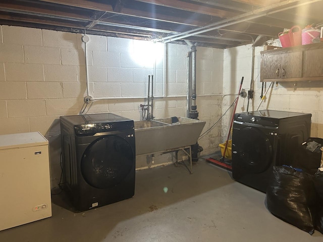 basement featuring refrigerator, washer and clothes dryer, and sink