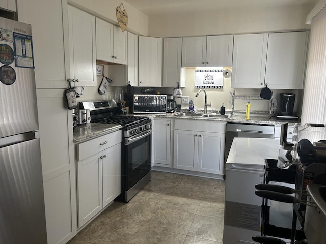 kitchen with white cabinetry, sink, light stone counters, and appliances with stainless steel finishes