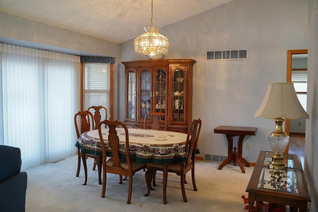 dining area featuring lofted ceiling, light carpet, and an inviting chandelier