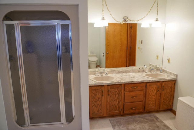 bathroom featuring tile patterned floors, vanity, toilet, and a shower with door