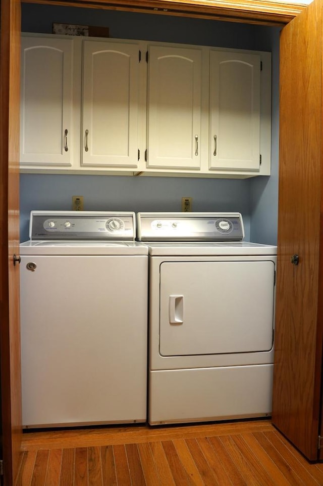 clothes washing area with washing machine and dryer and cabinets