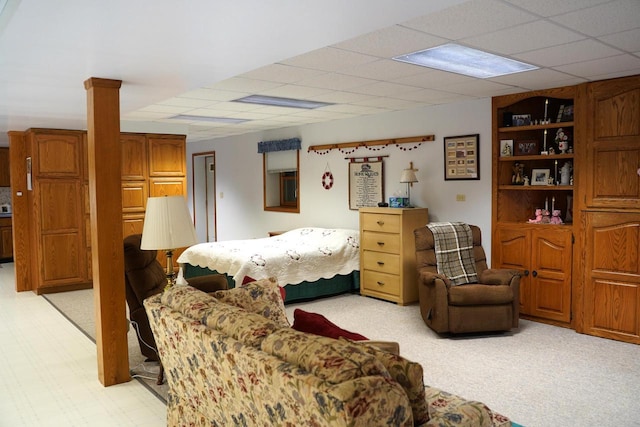 bedroom featuring decorative columns, light carpet, and a drop ceiling