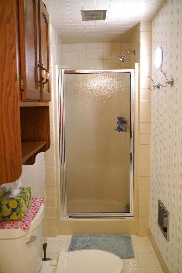 bathroom featuring toilet and a shower with shower door