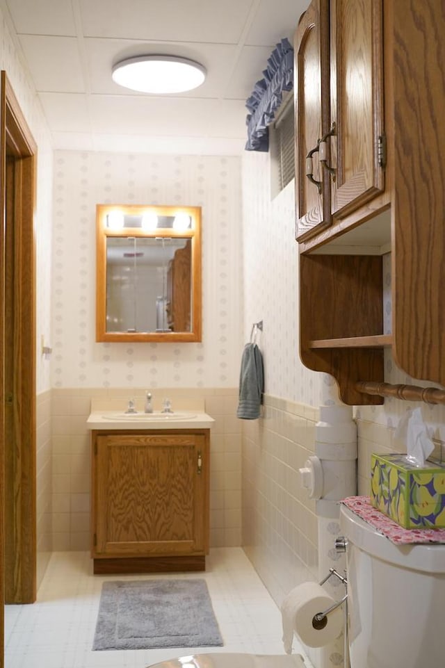 bathroom featuring vanity, toilet, tile patterned flooring, and tile walls