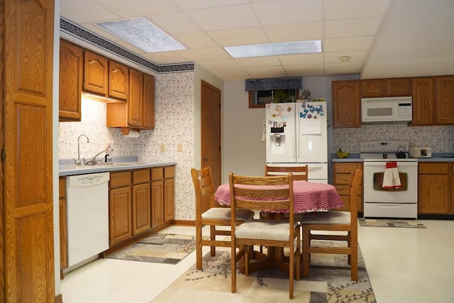 kitchen with white appliances, a paneled ceiling, sink, and backsplash