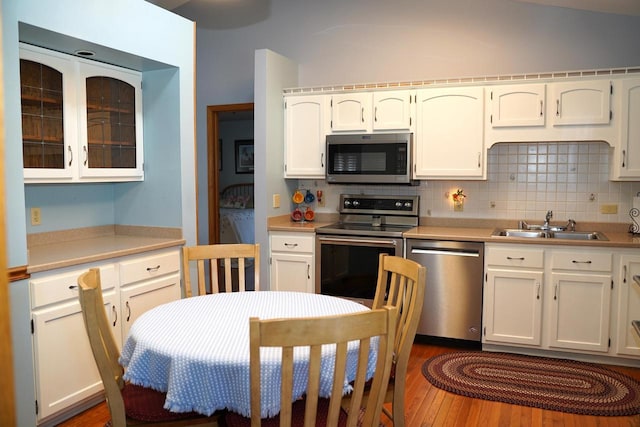 kitchen featuring sink, white cabinetry, appliances with stainless steel finishes, dark hardwood / wood-style flooring, and decorative backsplash