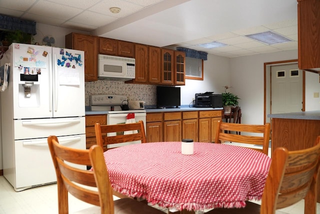 kitchen featuring backsplash, a drop ceiling, and white appliances