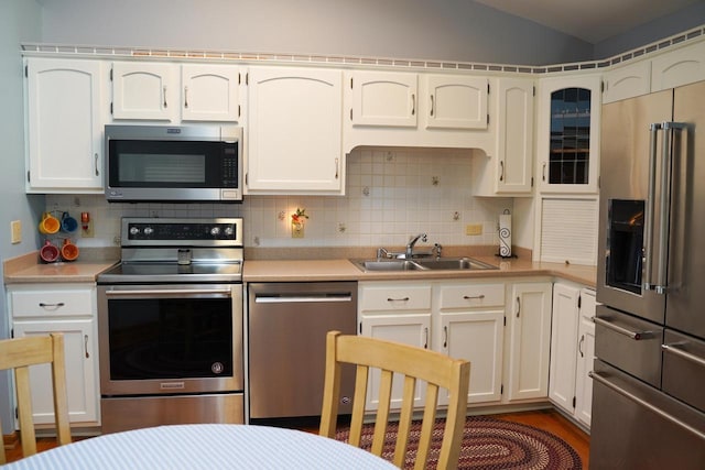 kitchen with lofted ceiling, appliances with stainless steel finishes, sink, and backsplash