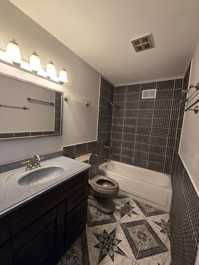 full bathroom featuring vanity, tile walls, toilet, and tiled shower / bath