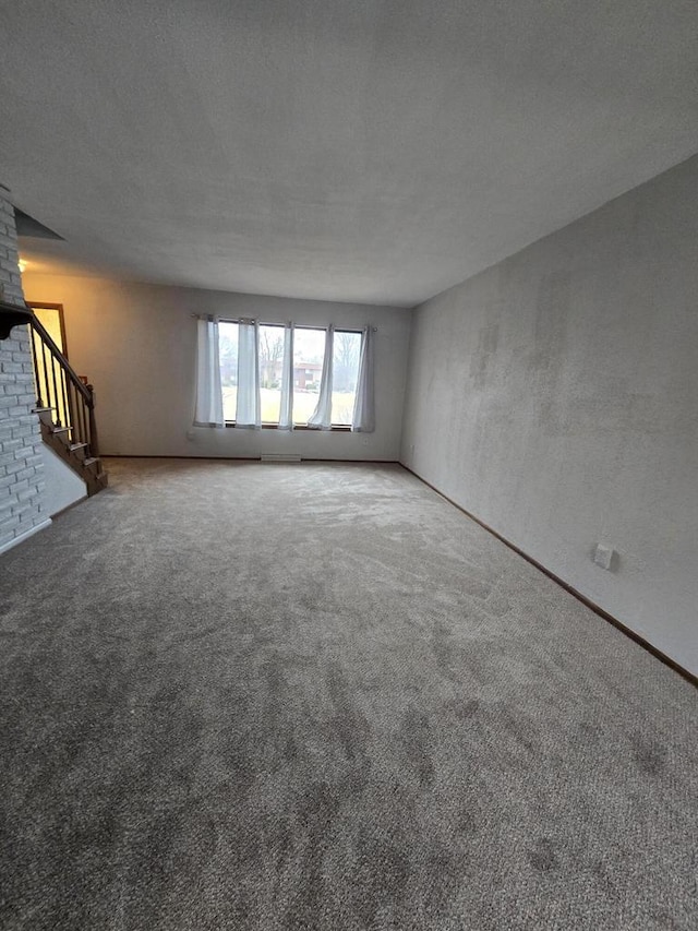 unfurnished living room featuring carpet flooring and a textured ceiling