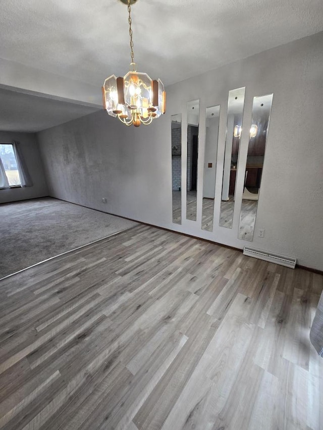 unfurnished dining area featuring an inviting chandelier, hardwood / wood-style flooring, and a textured ceiling