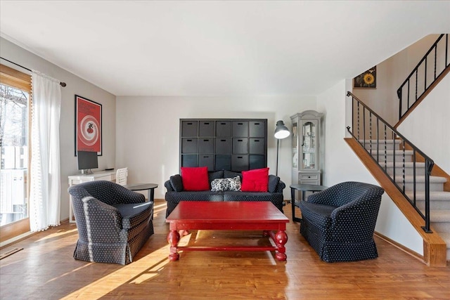 living room featuring baseboards, wood finished floors, and stairs