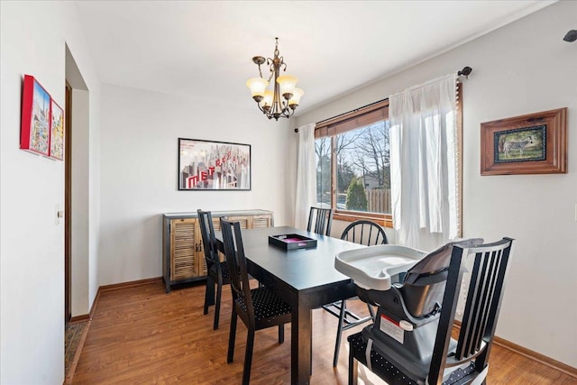 dining area featuring baseboards, a notable chandelier, and wood finished floors